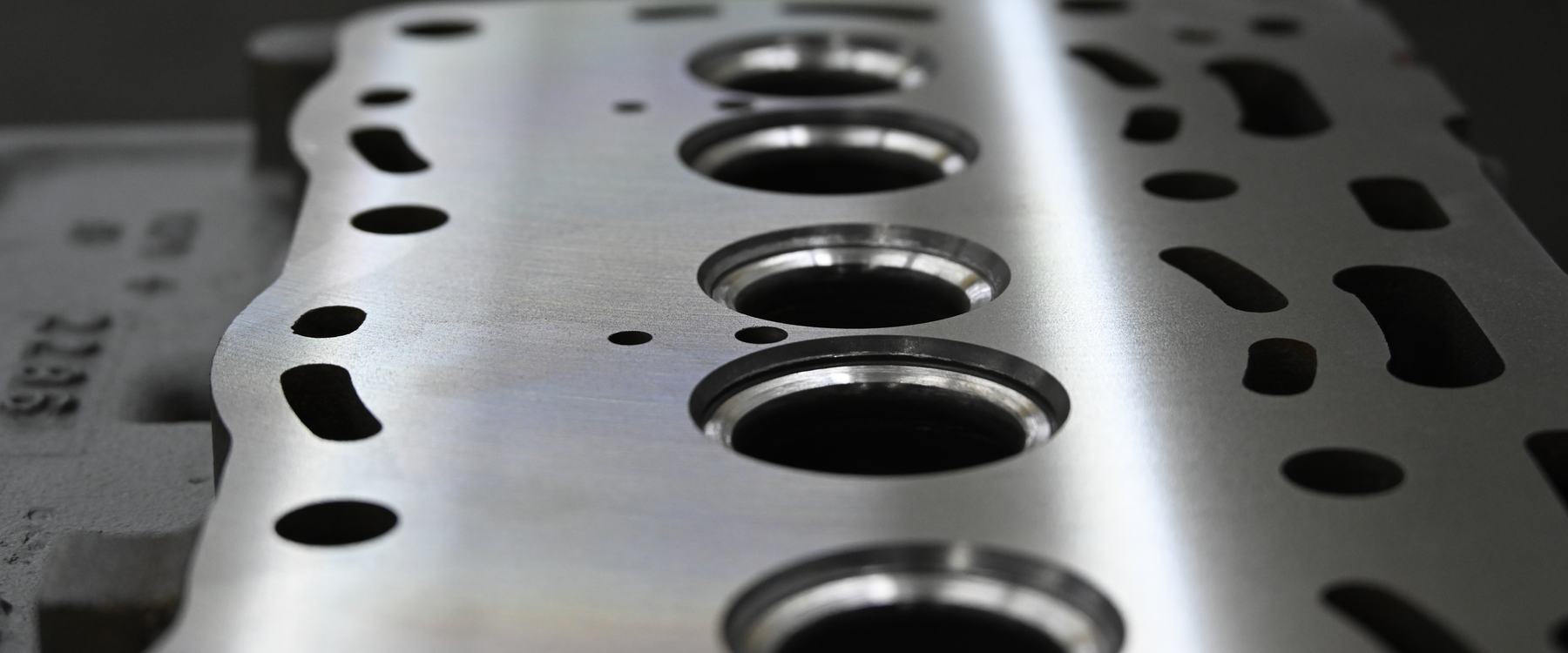 A freshly machined cylinder head deck, its counterbored cylinder openings and bolt holes catching raking light.