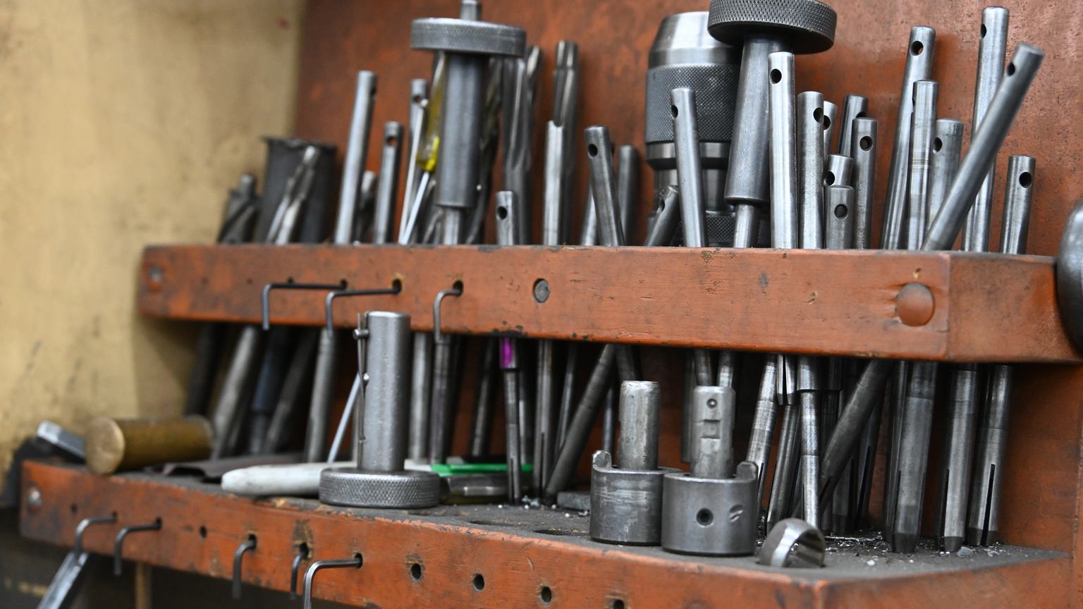 A steel tool rack at PDM holding reamers, drills, pilots and cutters.
