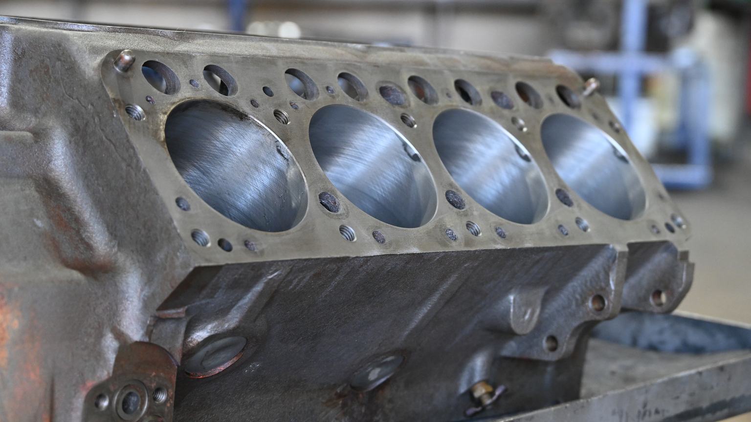 An engine block deck with four freshly honed cylinder bores showing the crosshatch pattern.