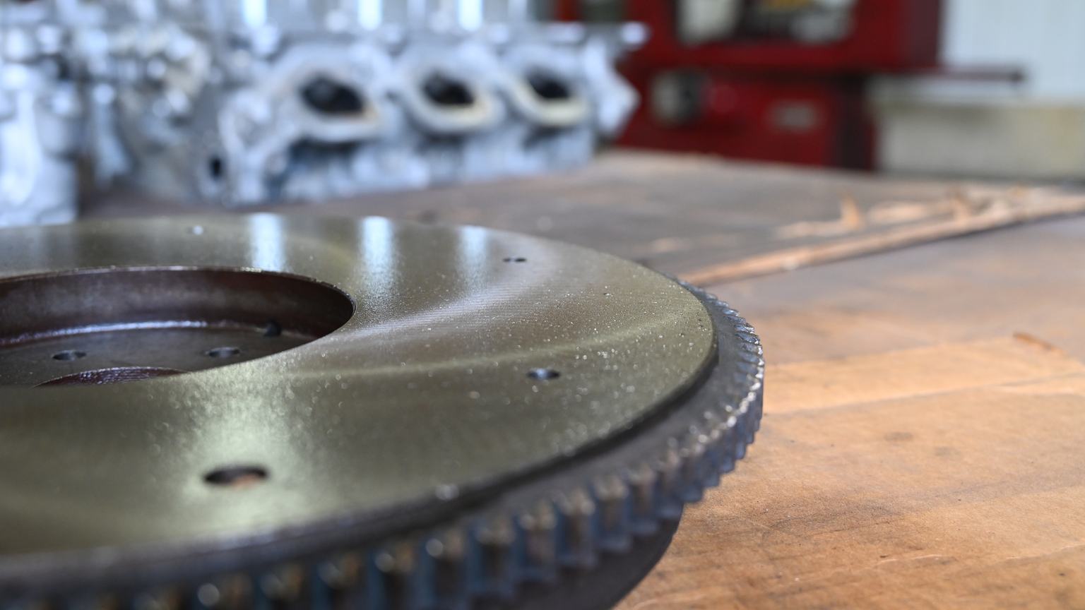 The ground friction surface and ring gear teeth of a flywheel on a workbench.